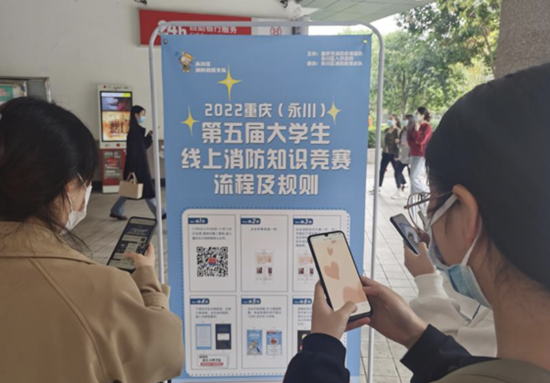 图为重庆文理学院学生正通过易拉宝宣传海报扫码答题